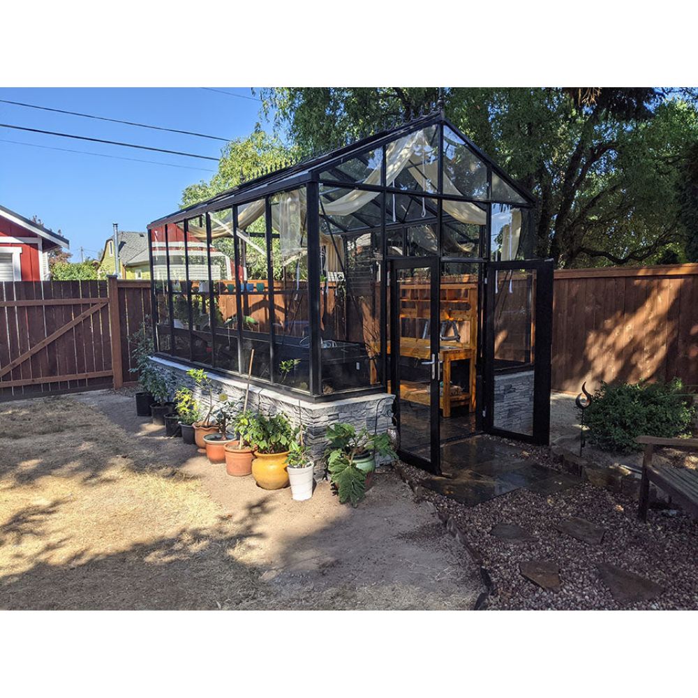 Greenhouse in a backyard with plants around it
