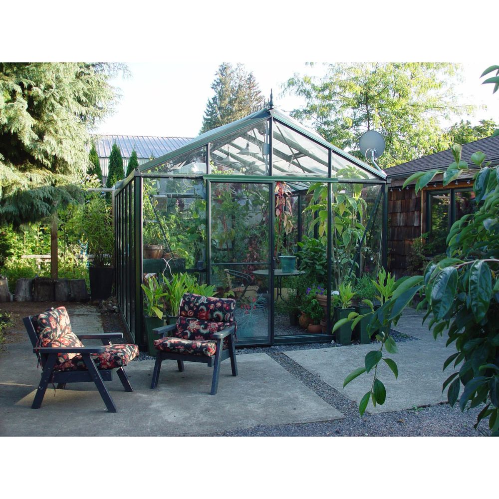Glass greenhouse in a garden with chairs and plants