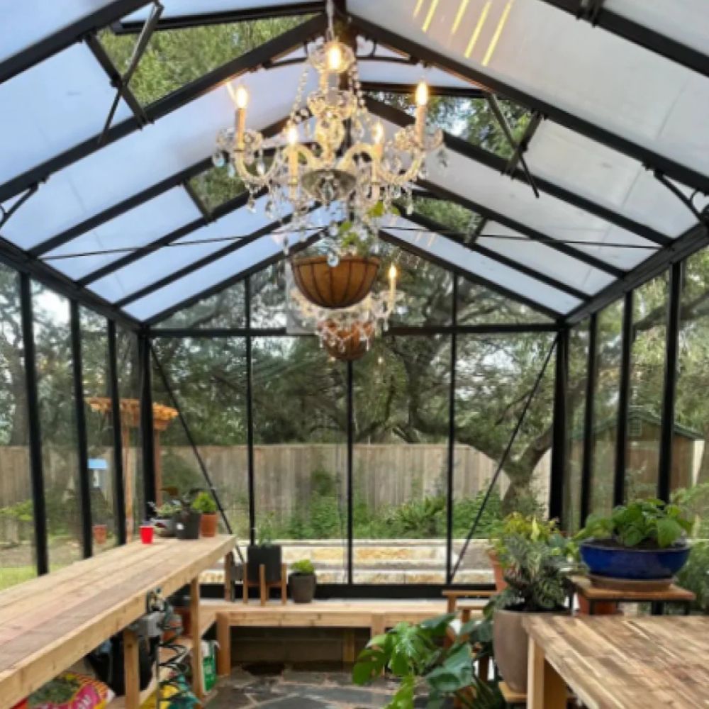 Greenhouse interior with a chandelier, tables, and plants