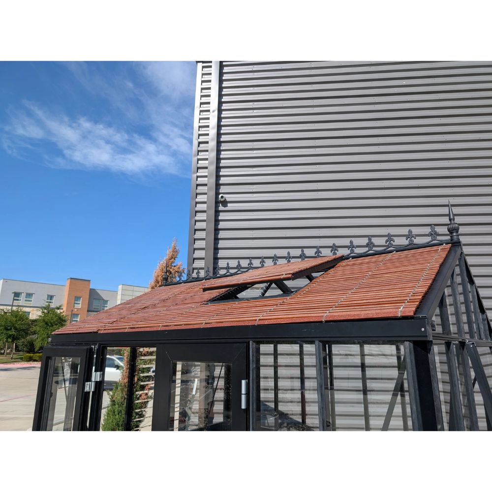 Modern building with a glass structure and metal roof against a blue sky.